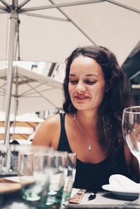 Smiling young woman sitting at sidewalk cafe