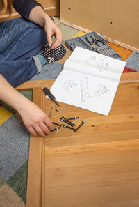 High angle view of man holding paper while sitting on table