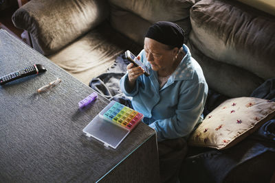 Senior woman sending voicemail through smart phone at home