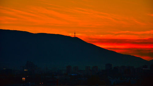 Silhouette buildings against sky during sunset