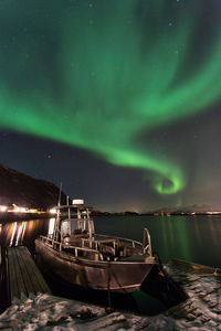 Boat moored in lake against sky at night