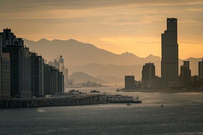 Sea in city against sky during sunset