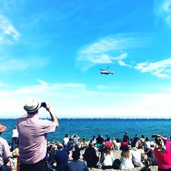 Rear view of people helicopter flying over sea against sky