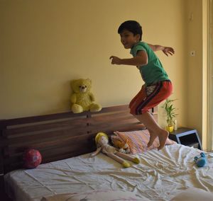 Full length of boy toys on bed at home