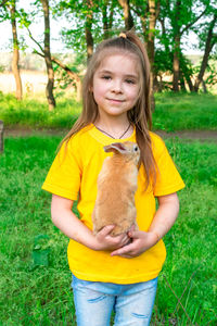 Portrait of young woman with dog on grassy field