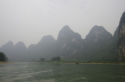 Scenic view of river and mountains against clear sky