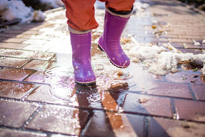 Low section of child splashing in puddle