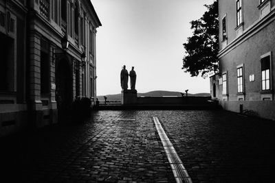 Silhouette people on street amidst buildings against sky