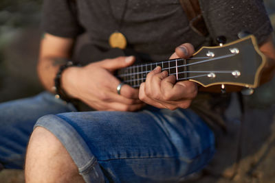 Midsection of man playing guitar