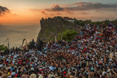 High angle view of people at traditional festival by sea during sunset
