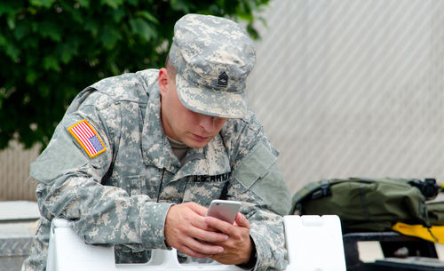 Soldier checks messages on his cell phone far from home