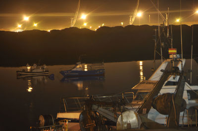 Sailboats moored on sea against sky at night