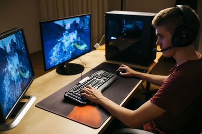 Young man playing video games with computer at desk