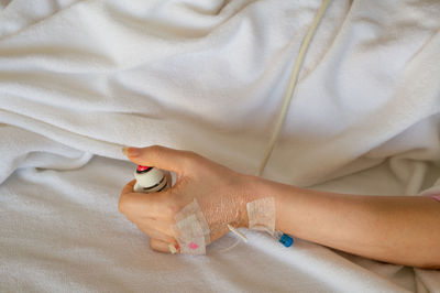 Midsection of woman with iv drip holding panic button on bed at hospital