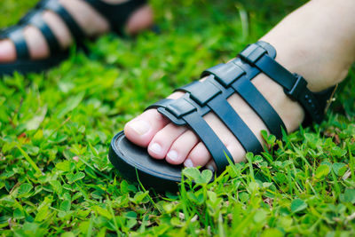 Low section of person wearing sandal on grassy field