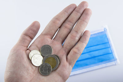 Close-up of hand holding coin against white background