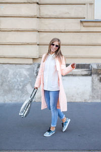 Full length of young woman standing against wall
