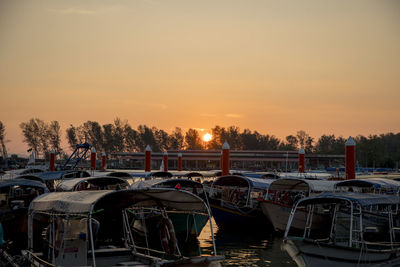 Boats moored at marina during sunset