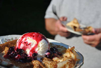 Midsection of person with pancake and ice cream in plate