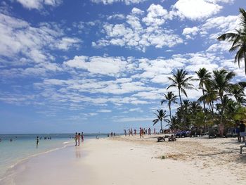 People at beach against sky during summer