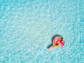 High angle view of woman lying on inflatable raft in swimming pool