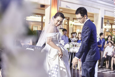 Side view of couple looking down while standing against people during wedding