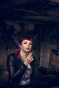 Portrait of young woman smoking standing in abandoned building