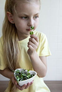 Little girl holding a bowl with microgreens in her hands. healthy eating concept
