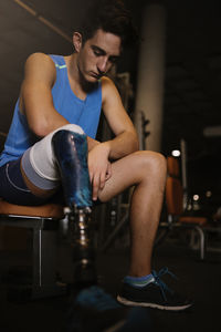 Man with artificial leg sitting in gym