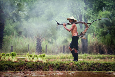 Farmer carrying equipment while walking on agricultural field