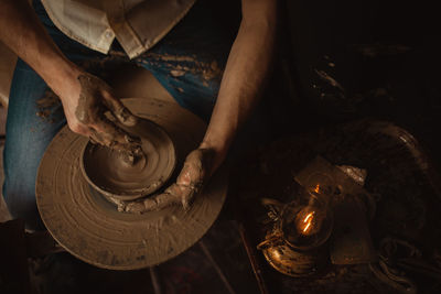 Man in pottery workshop makes plate of clay, an authentic atmosphere, yellow lamp, lifestyle, 