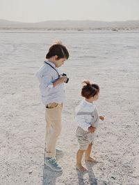 Portrait of a kid holding a camera as another kid stands next him