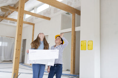 Girl holding plan standing at construction site