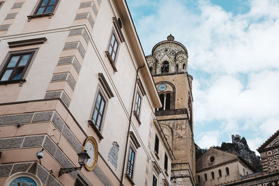 Low angle view of clock tower amidst buildings against sky