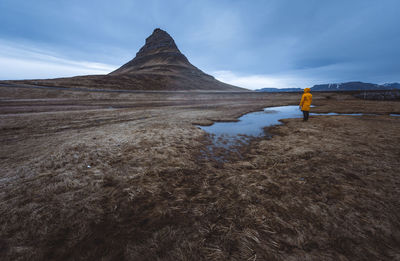 Man standing on land by puddle against sky