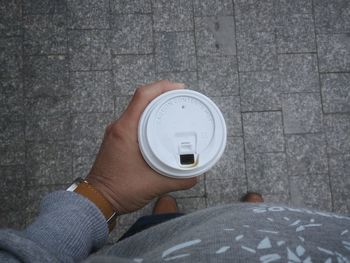 Low section of man having coffee while standing on footpath