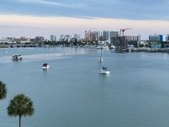 High angle view of sailboats in sea by buildings against sky