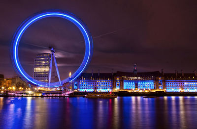 Illuminated ferris wheel in city at night