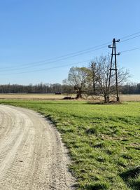 Road amidst field against clear sky