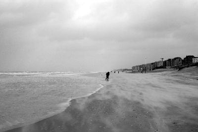 Man walking on beach against sky