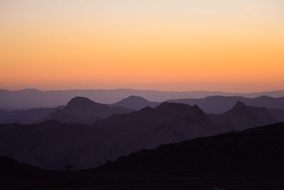 Scenic view of silhouette mountains against orange sky