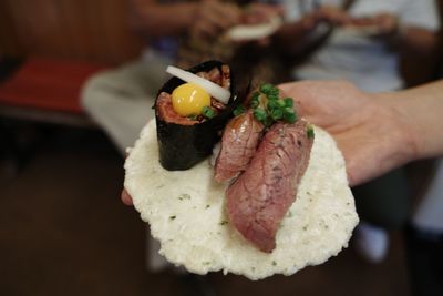 Close-up of hand raw beef sushi