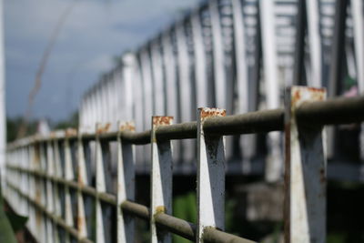 Close-up of metal fence against bridge