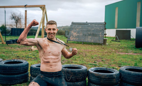 Portrait of shirtless man flexing muscle outdoors