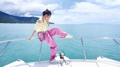 Woman standing on boat sailing in sea against sky