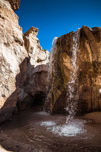 Water flowing through rocks against clear blue sky