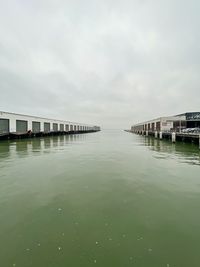 Pier over river by buildings against sky