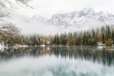 Scenic view of lake by snowcapped mountains against sky