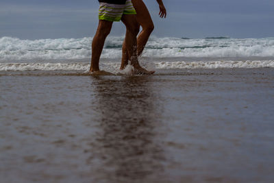 Low section of man walking on beach