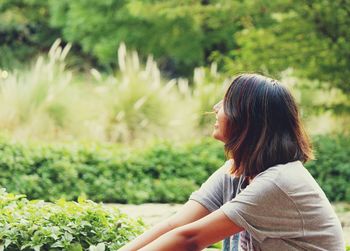 Teenage girl sitting by plants at park